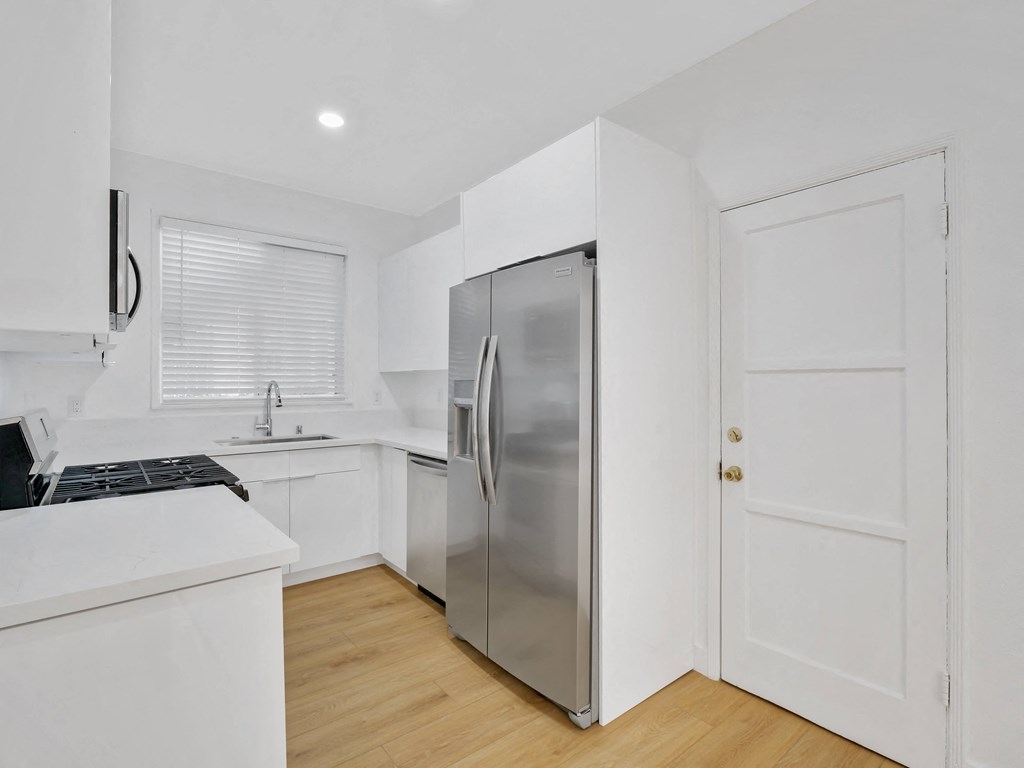 a kitchen with white cabinets and a stainless steel refrigerator