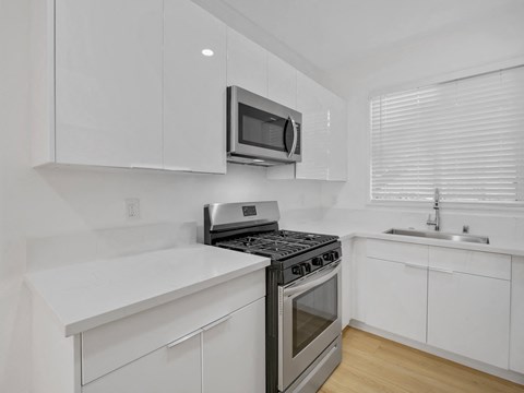 an all white kitchen with stainless steel appliances and a microwave