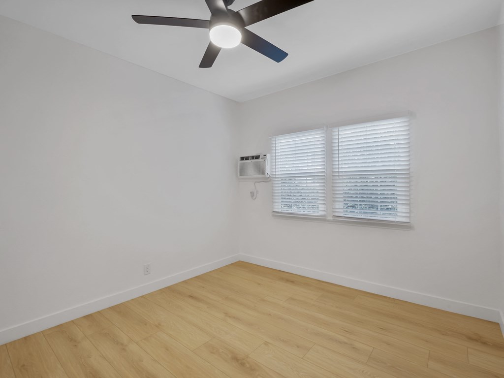 an empty room with white walls and a ceiling fan