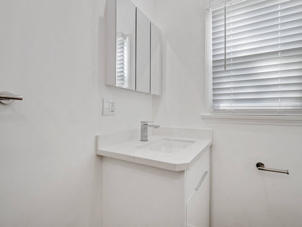 a bathroom with a sink and a mirror and a window