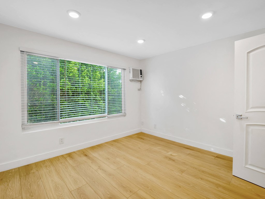 a bedroom with hardwood floors and a large window