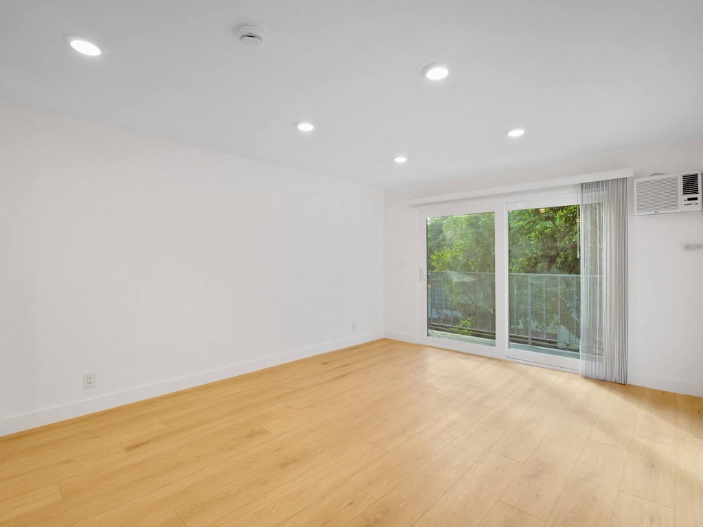 a bedroom with a sliding glass door and hardwood floors