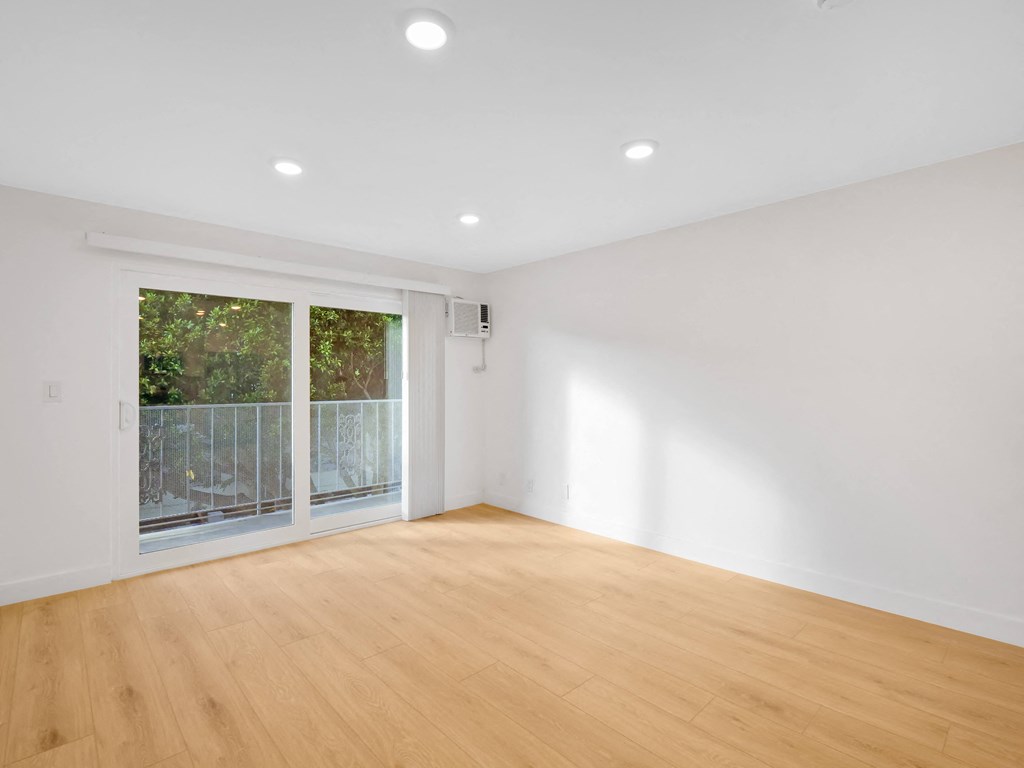 a bedroom with a sliding glass door and hardwood floors