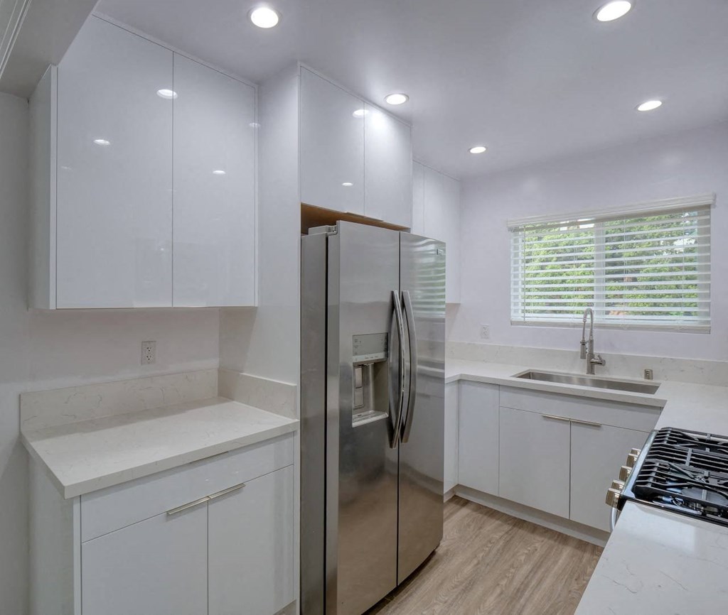 a kitchen with white cabinets and a stainless steel refrigerator