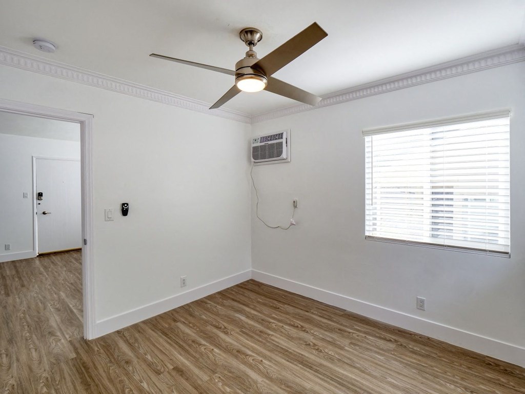 an empty bedroom with a ceiling fan and a window