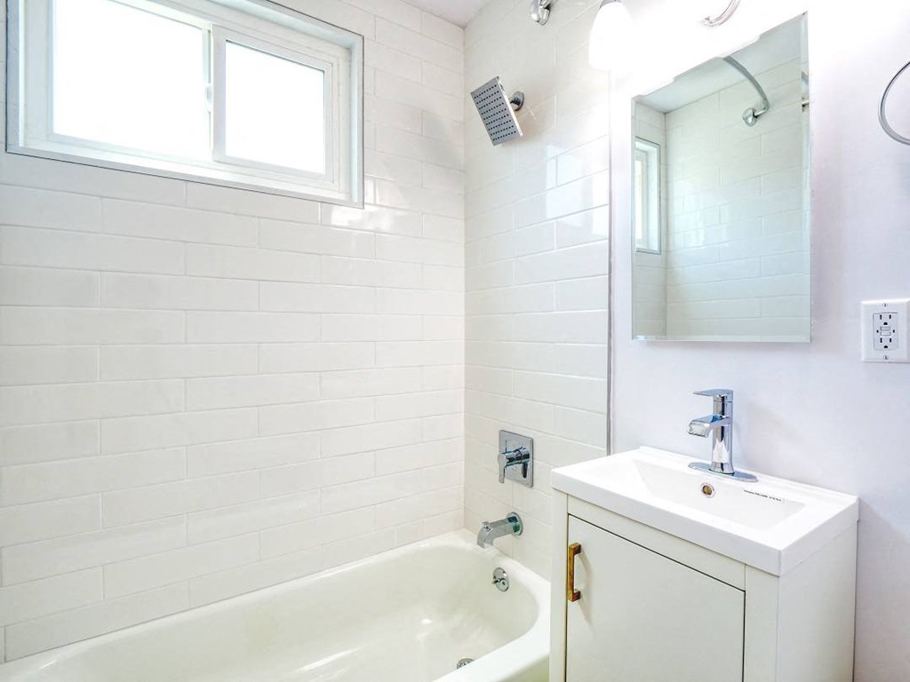 a white bathroom with a sink and a bath tub