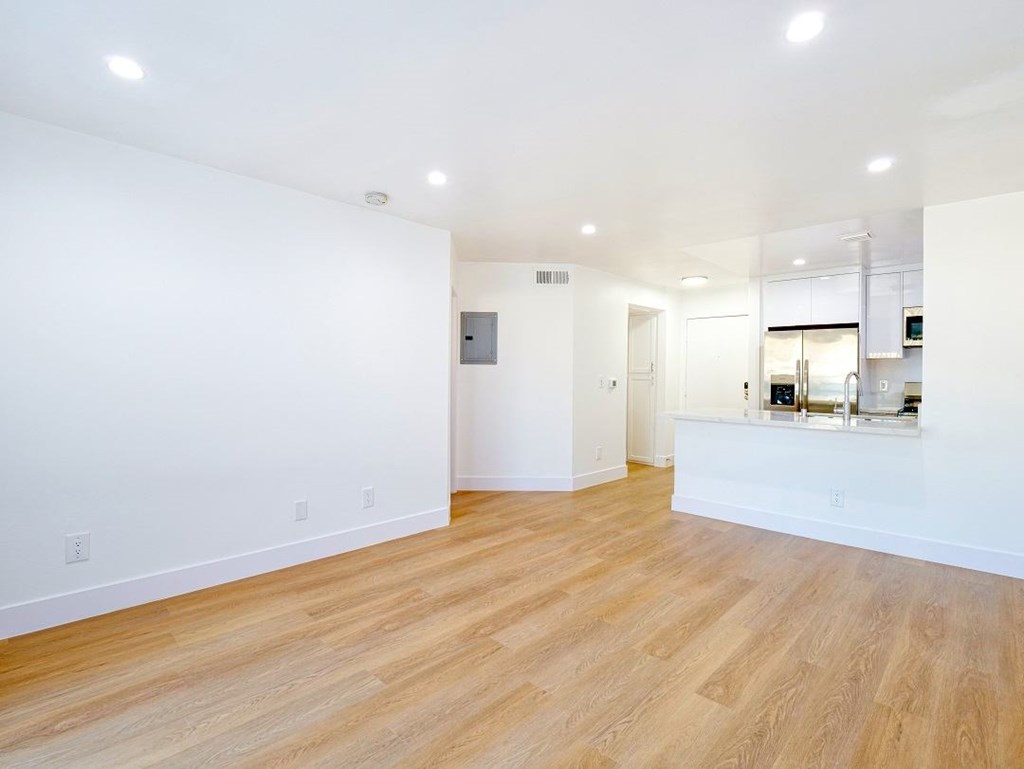 an empty living room and kitchen with a hard wood floor