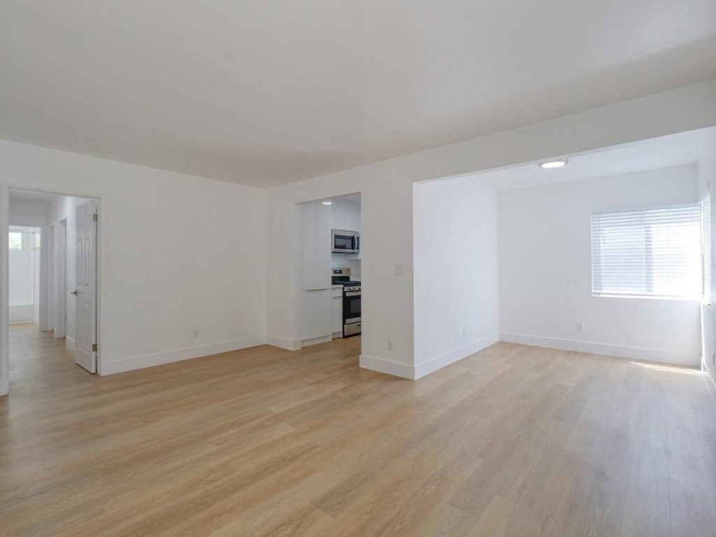 the living room and kitchen of an empty house with wood floors
