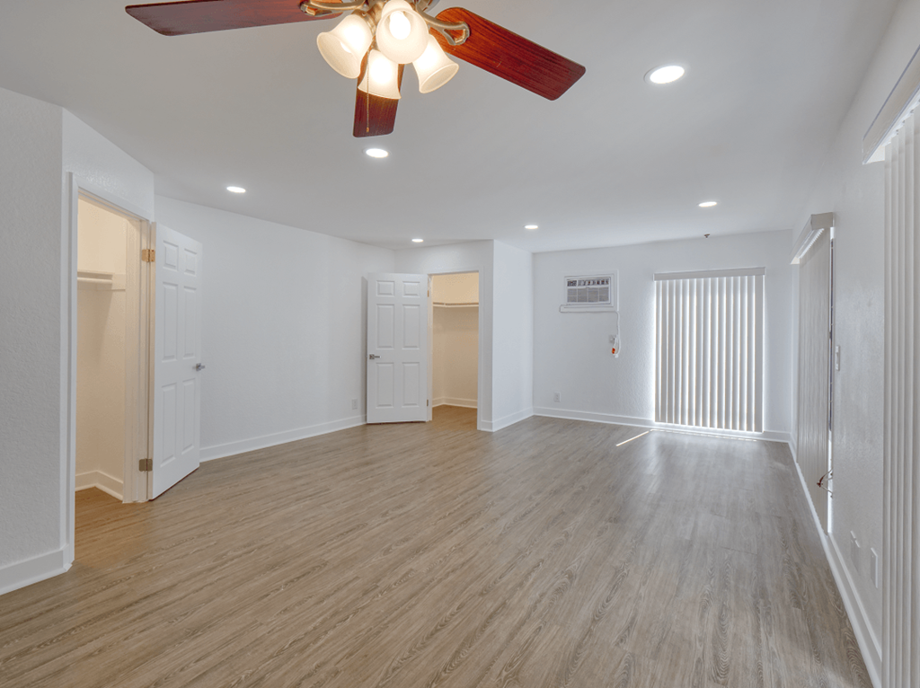 an empty living room with a ceiling fan and a closet