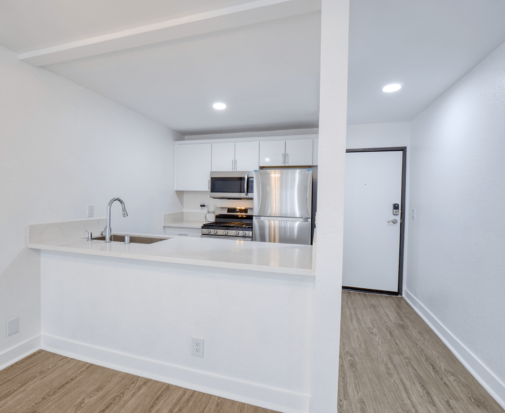 an empty kitchen with a counter top and a refrigerator