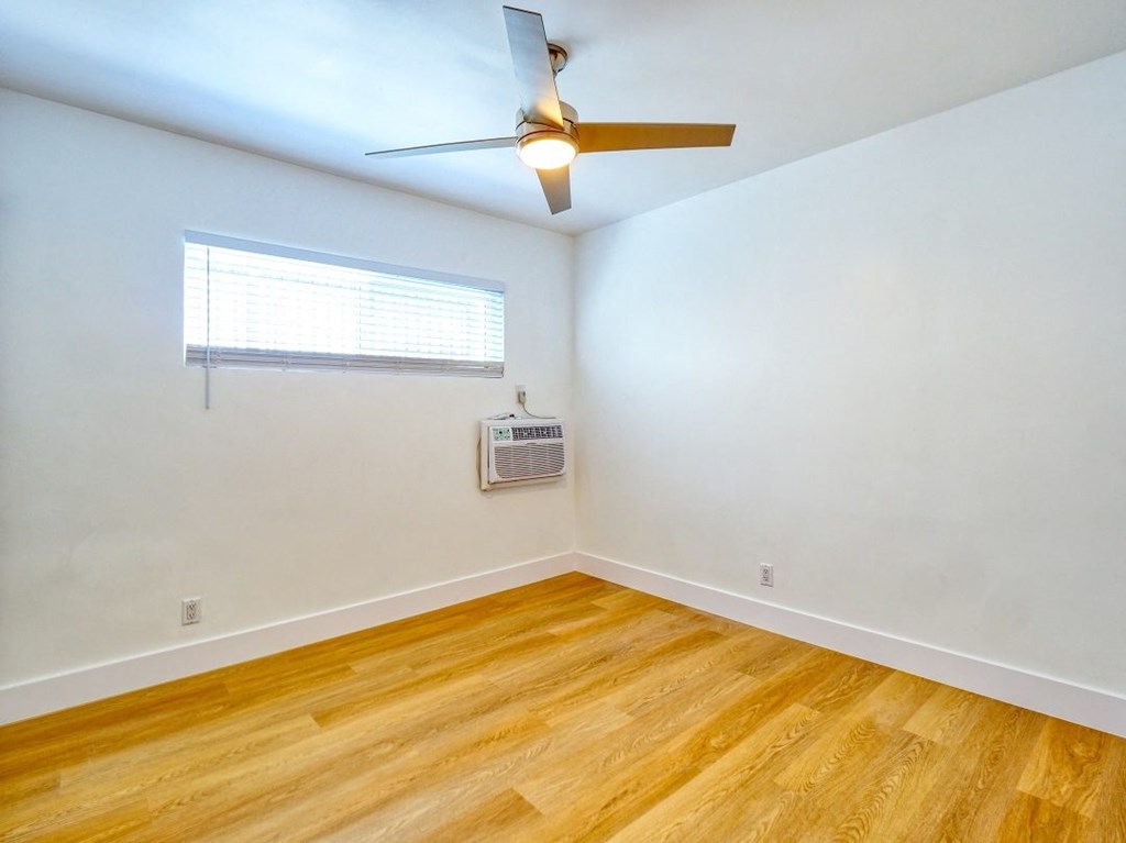 an empty room with wood floors and a ceiling fan