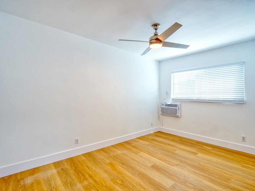 an empty bedroom with a ceiling fan and a window