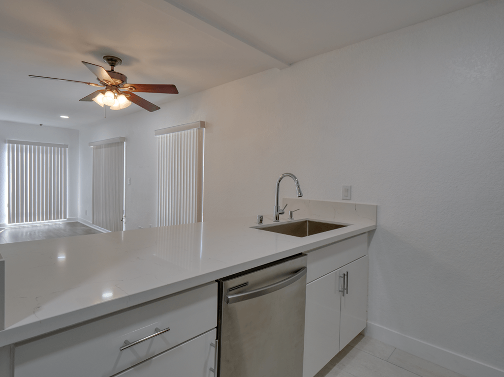 an empty kitchen with a sink and a ceiling fan