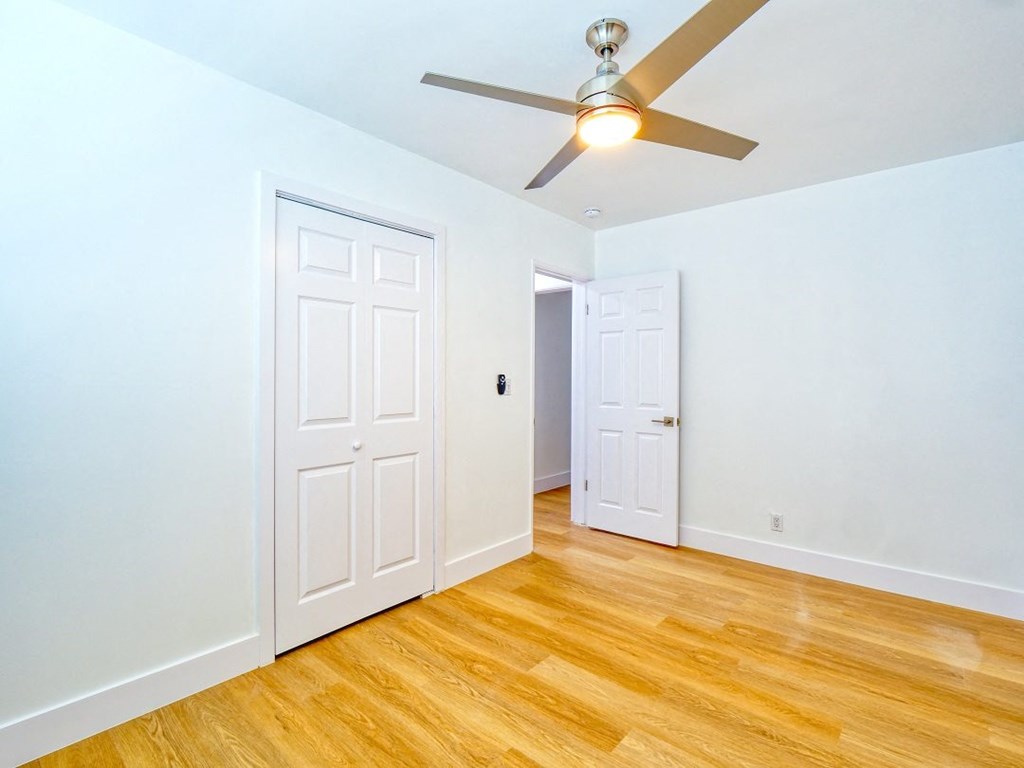 a bedroom with a ceiling fan and a door to a closet