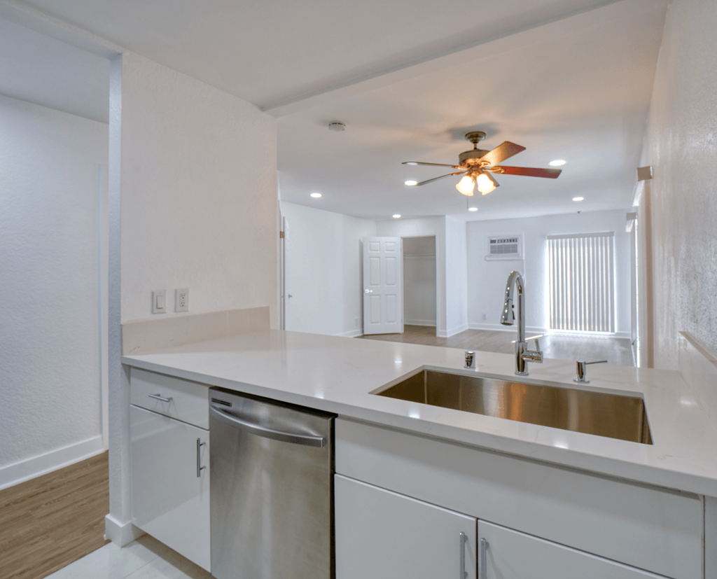an empty kitchen with a sink and a ceiling fan