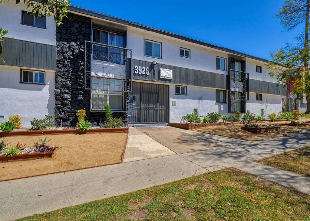 front view of an apartment building with a sidewalk and landscaping