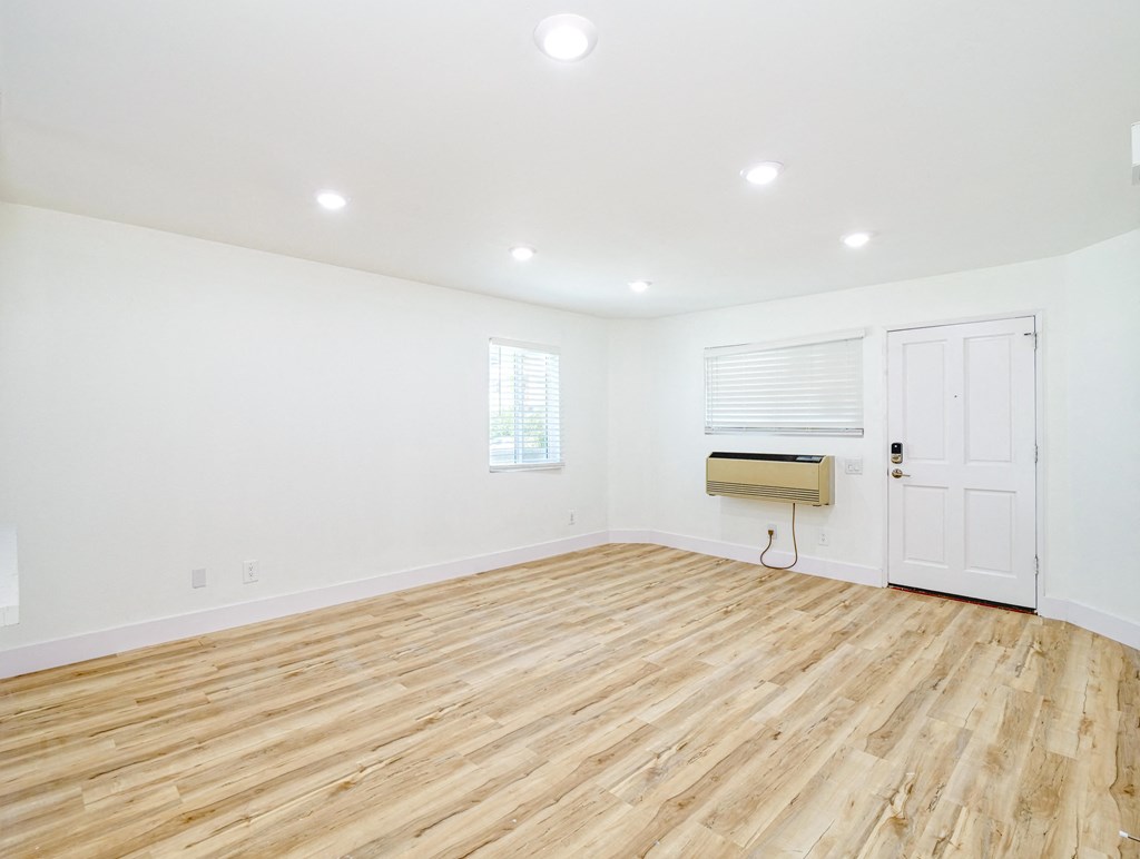 an empty living room with wood floors and white walls
