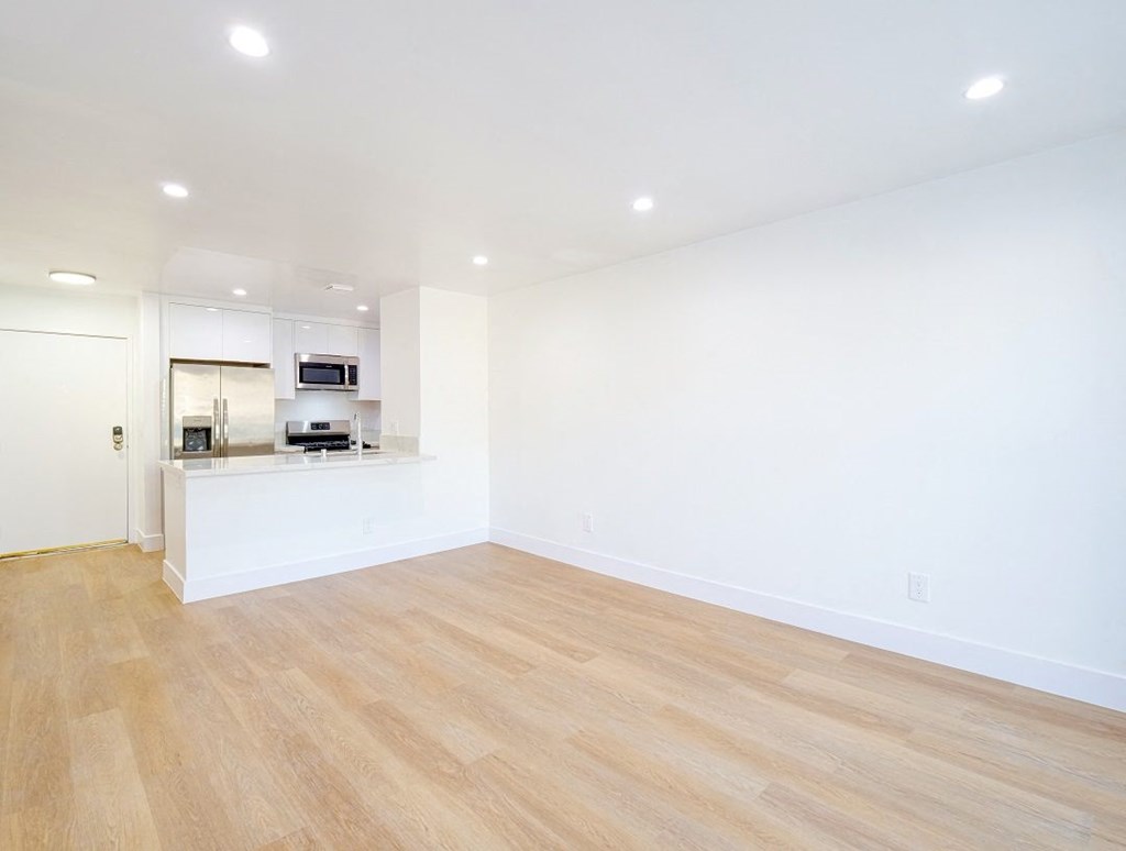an empty living room and kitchen with wood flooring