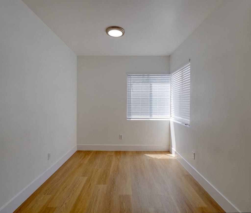 a living room with white walls and a window and wooden floors