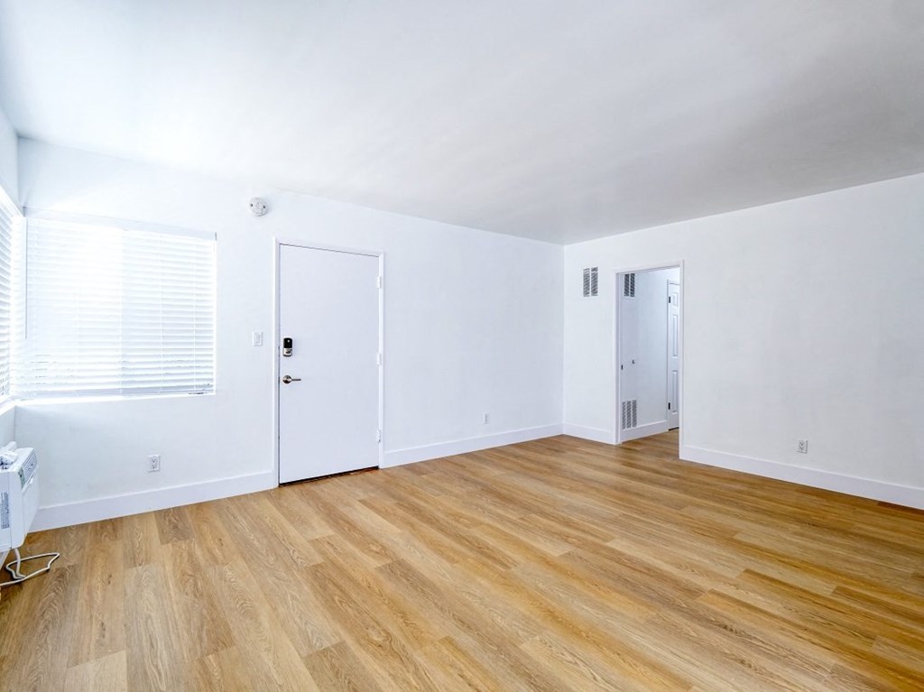 an empty room with white walls and a wood floor