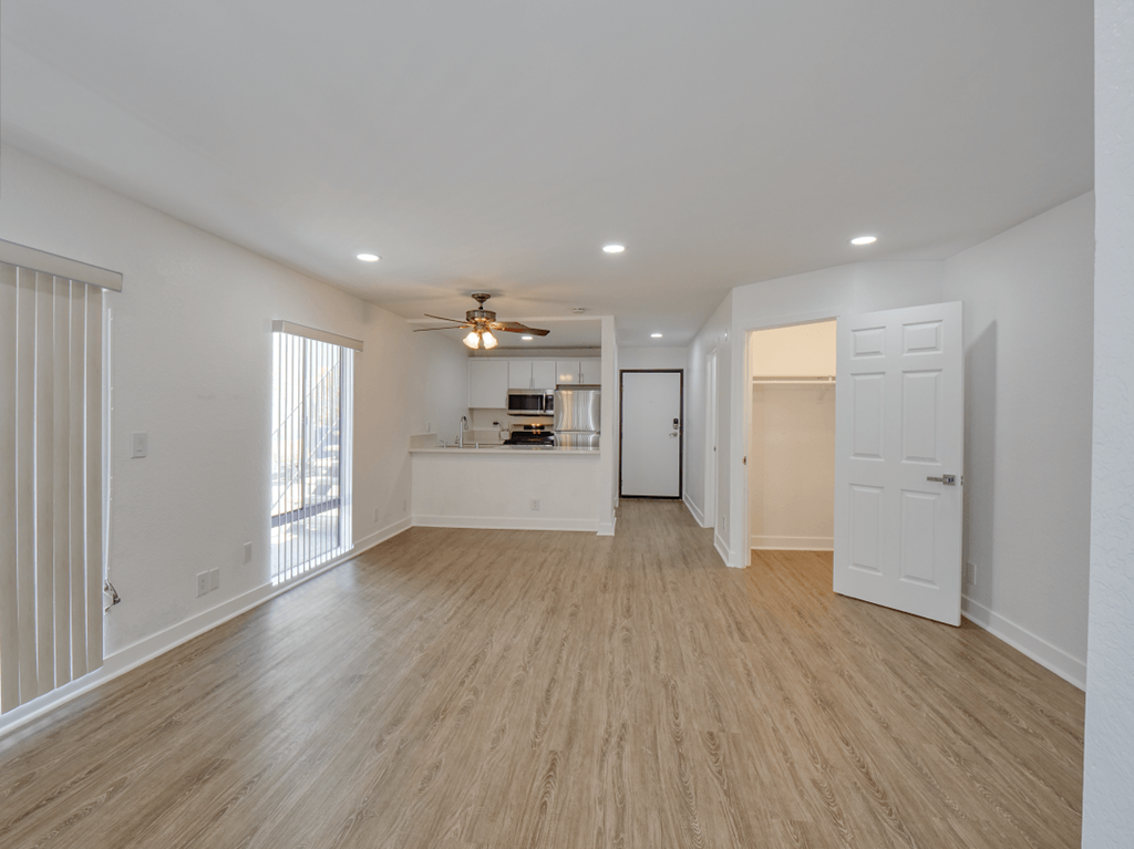 an empty living room and kitchen with a ceiling fan