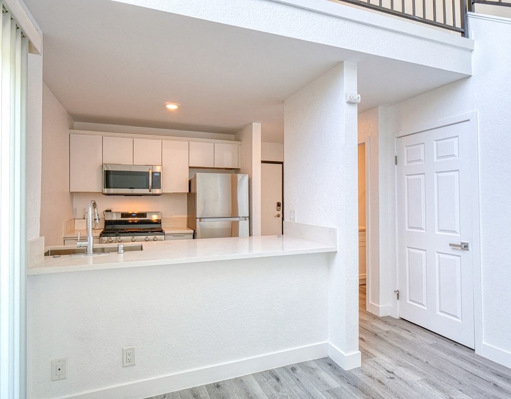 an open kitchen and living room with a white counter top