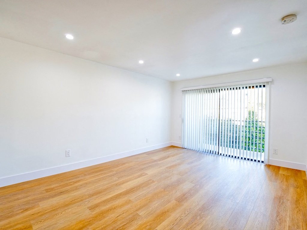 an empty living room with a large window and wood floors