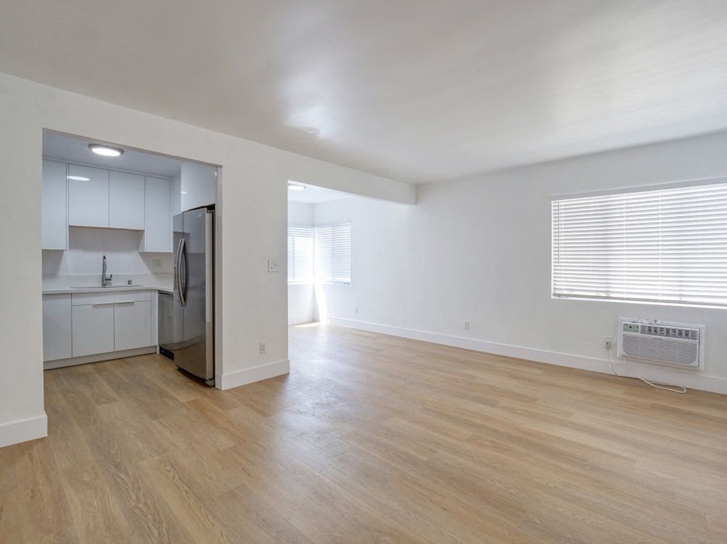 the living room and kitchen of an empty house with wood flooring