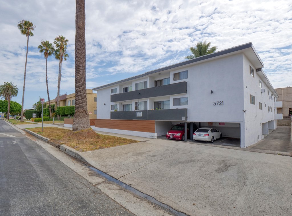 a white apartment building with a parking lot and palm trees