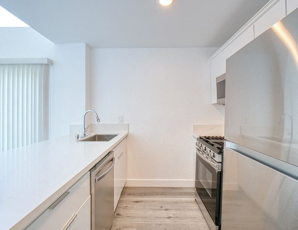 a renovated kitchen with stainless steel appliances and white counter tops