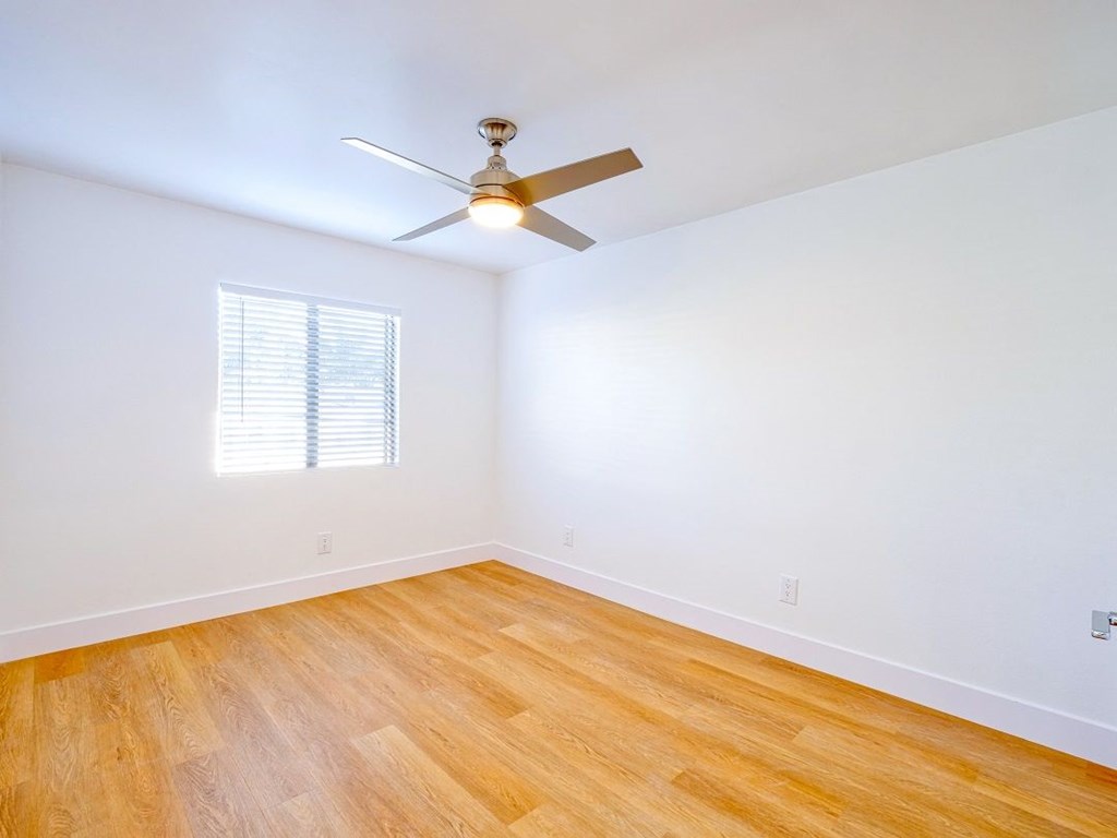 an empty room with a ceiling fan and wood floors