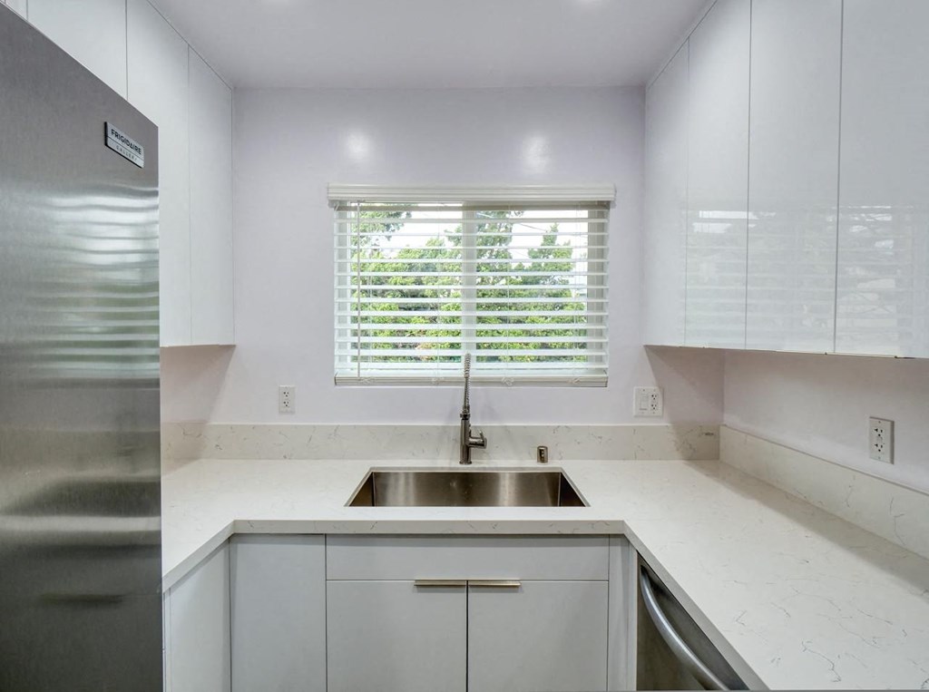 a white kitchen with a sink and a window