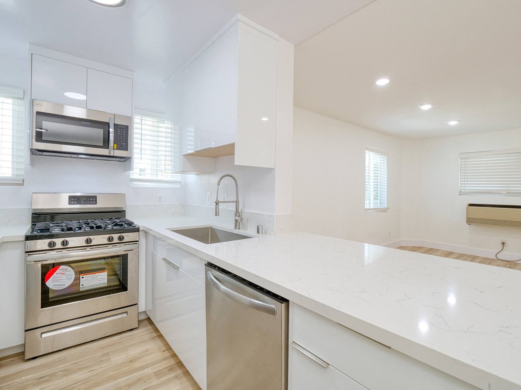 a white kitchen with stainless steel appliances and a white counter top