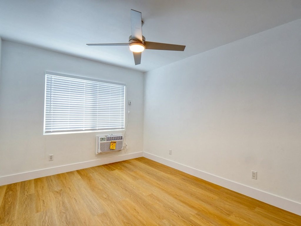 an empty room with a ceiling fan and a window
