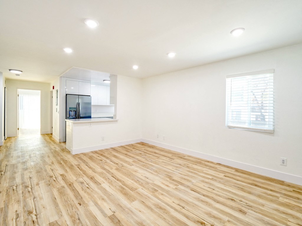 the living room and kitchen of an empty house with wood flooring