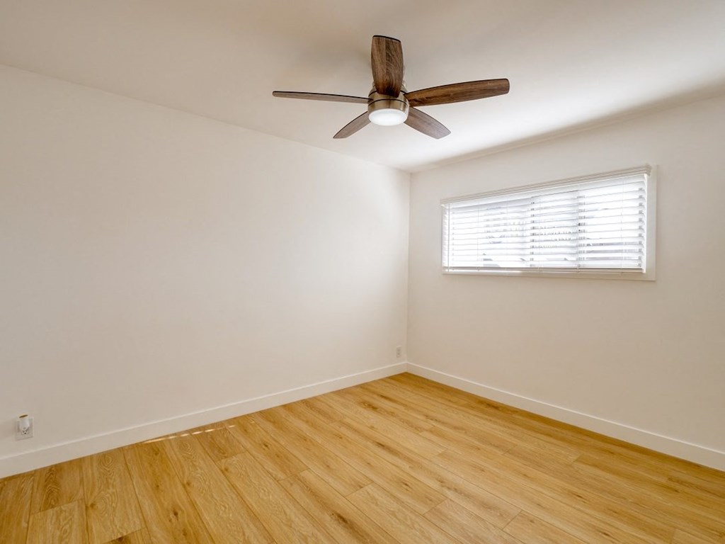 an empty room with a ceiling fan and a window