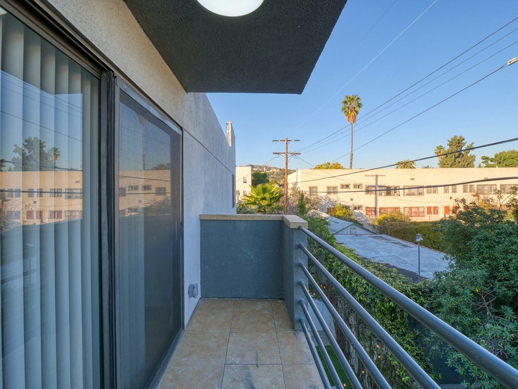 the view from the balcony of a condo with a view of the street and trees