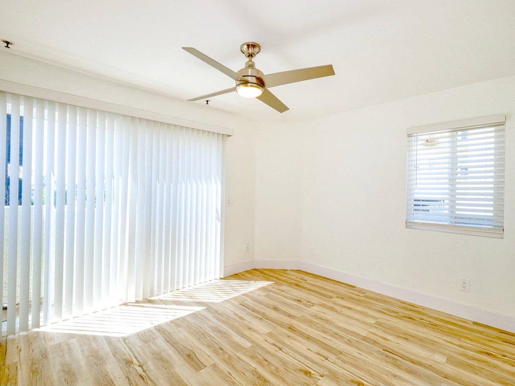 an empty living room with a ceiling fan and a window