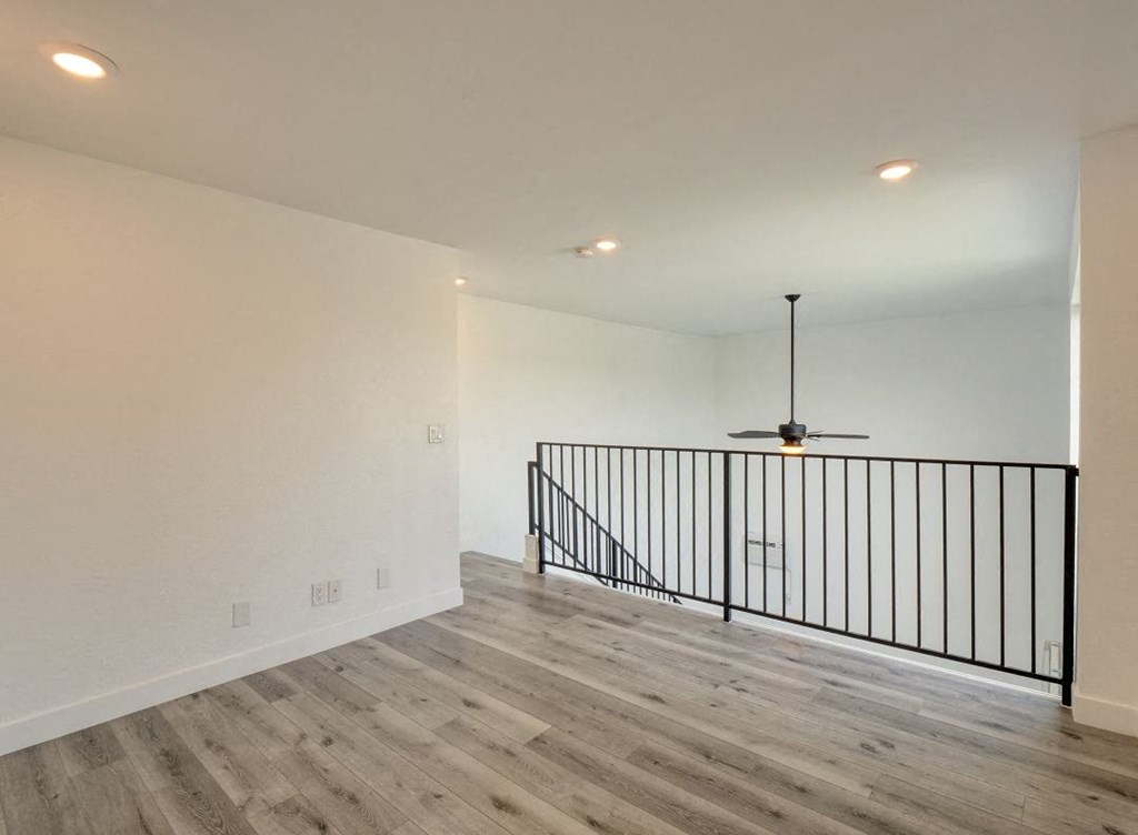 a living room with a railing and a ceiling fan