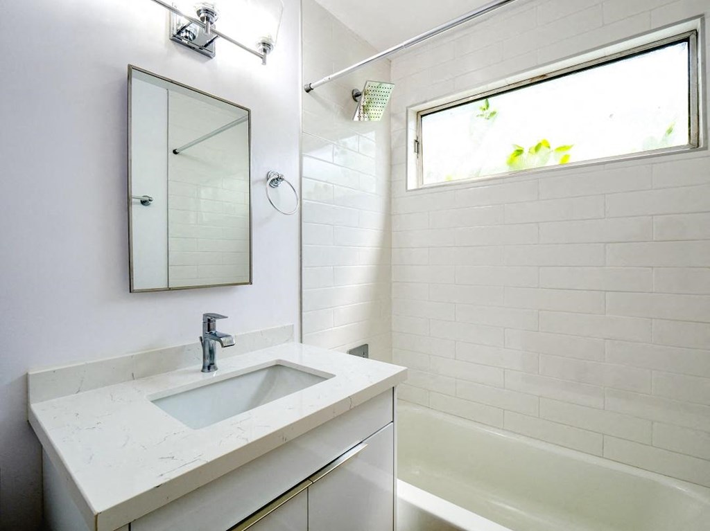 a bathroom with a sink and a mirror and a tub
