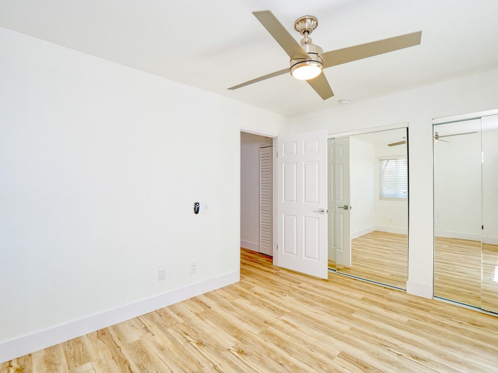 an empty living room with a ceiling fan and a mirror