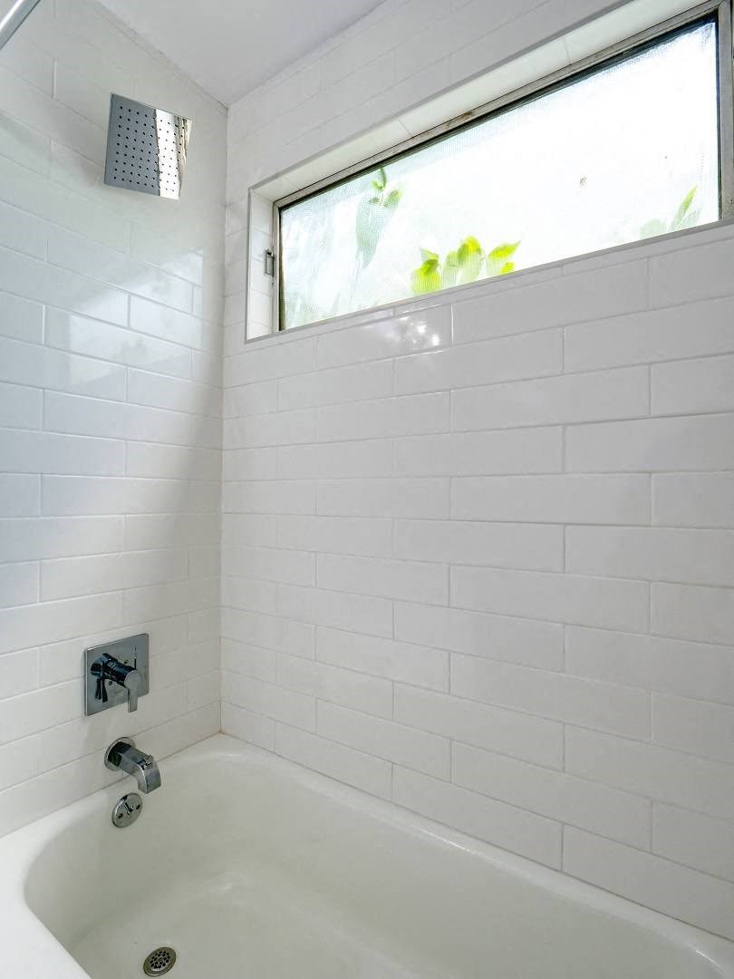 a white bathroom with a tub and a window