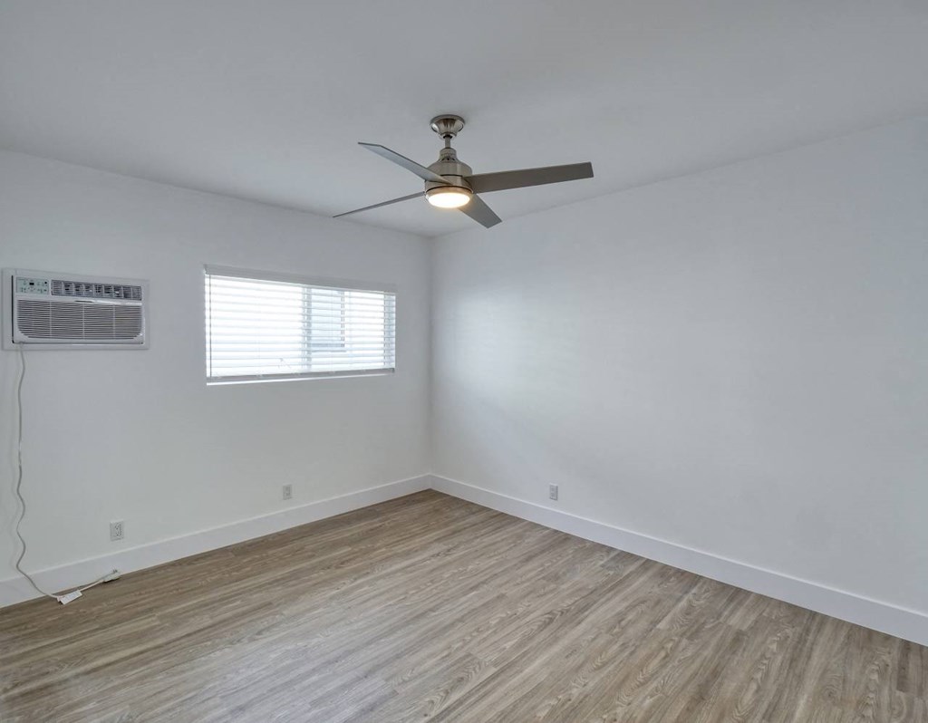an empty room with a ceiling fan and a window