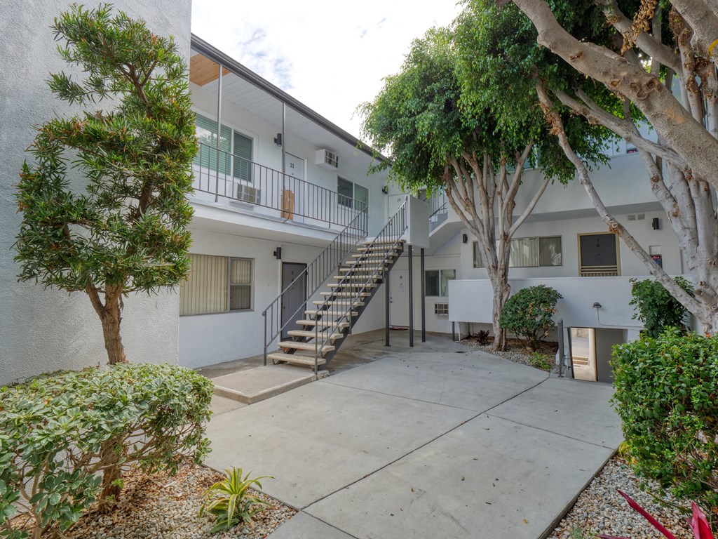 the courtyard of an apartment building with stairs and trees