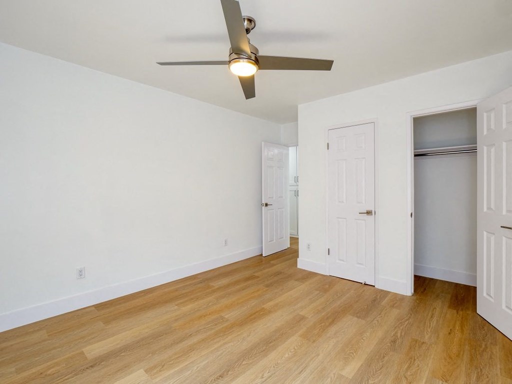 an empty living room with a ceiling fan and a closet
