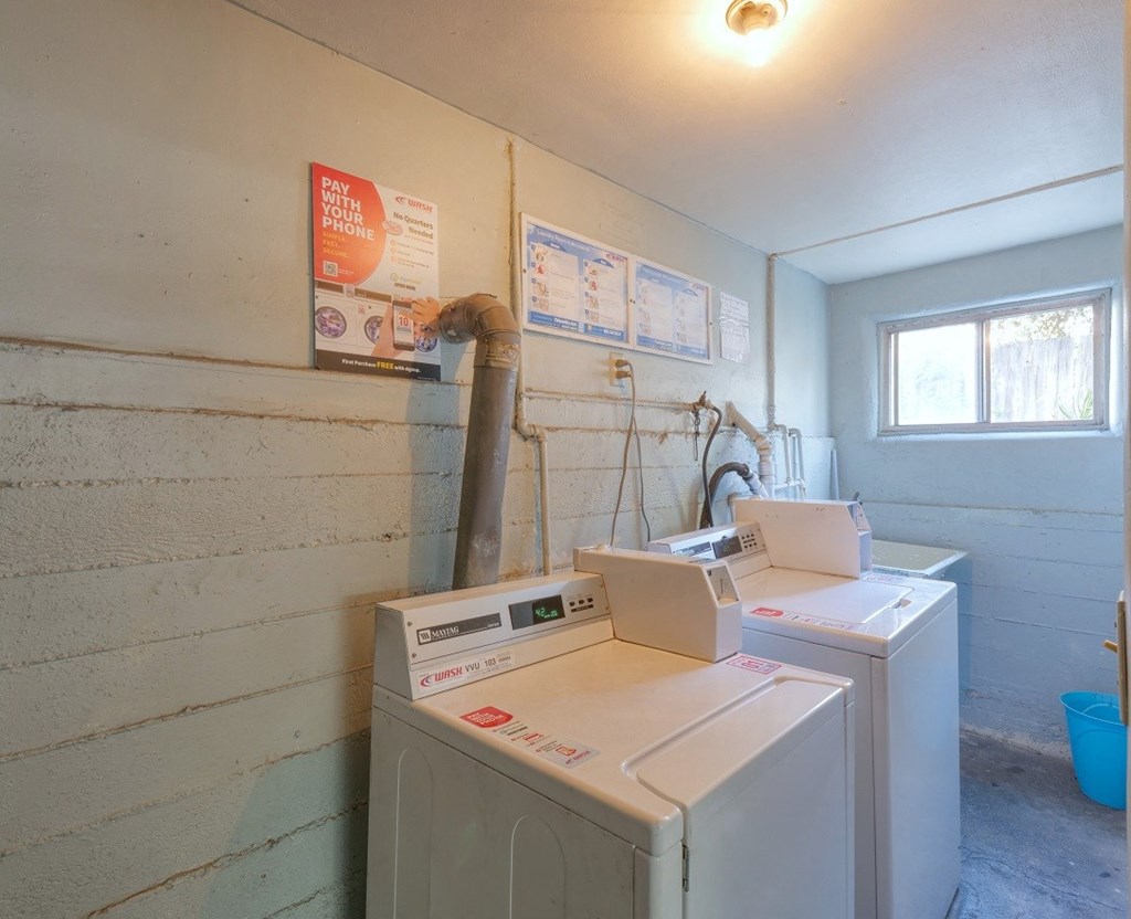 a laundry room with two washing machines and a window