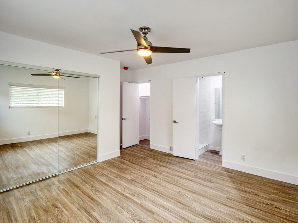 an empty living room with a ceiling fan and a mirror