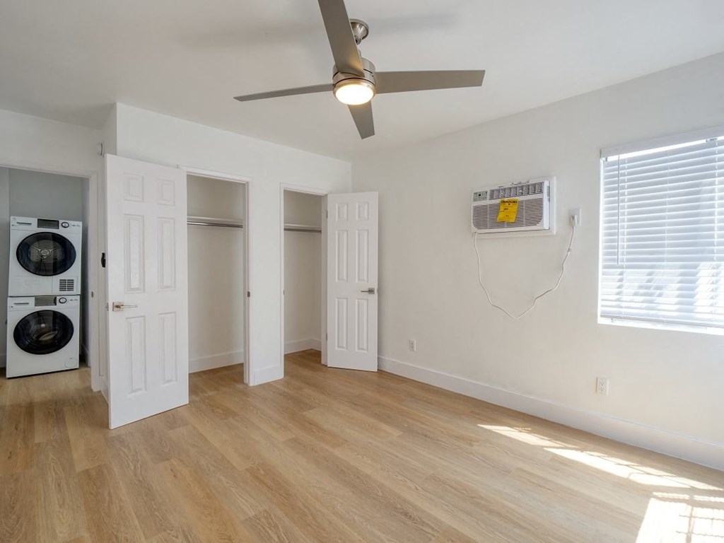 an empty living room with a ceiling fan and a washer and dryer