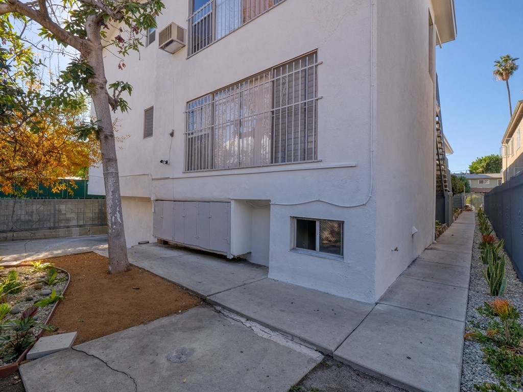 a white apartment building with a sidewalk and a window