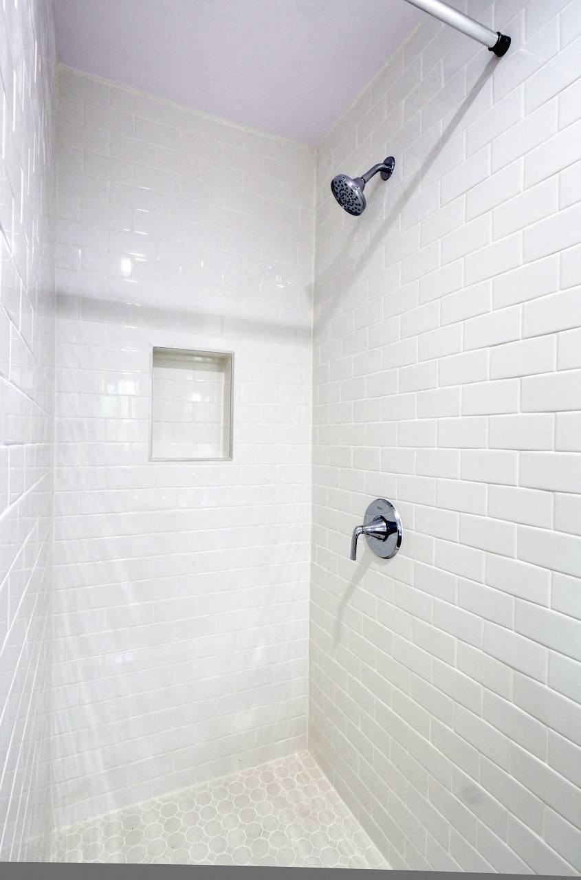 a white tiled shower in a small white bathroom